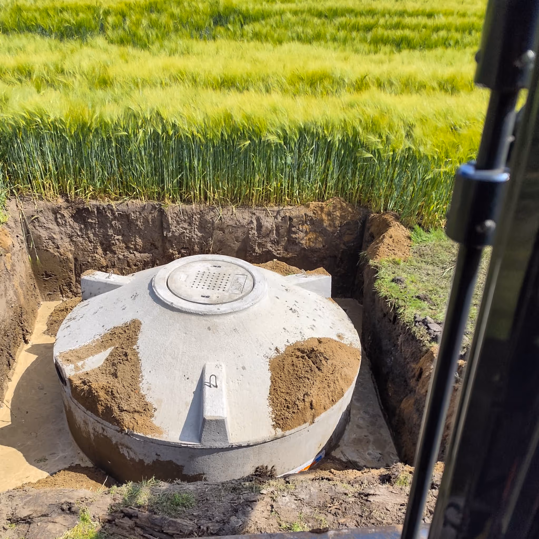 Betonbehälter einer Kleinkläranlage in der Baugrube am Feldrand