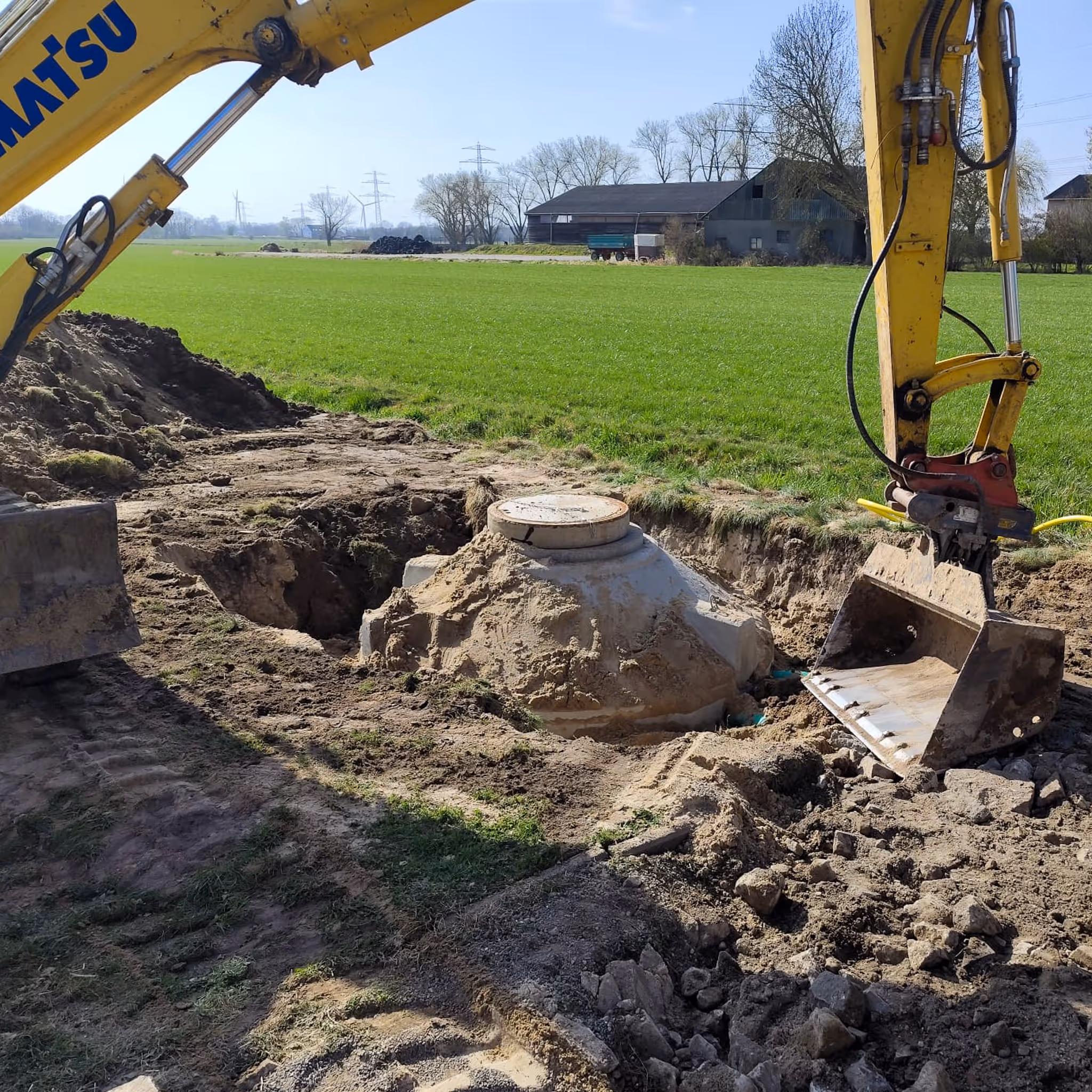 Bagger setzt Kläranlagenbehälter in eine Baugrube auf dem Land