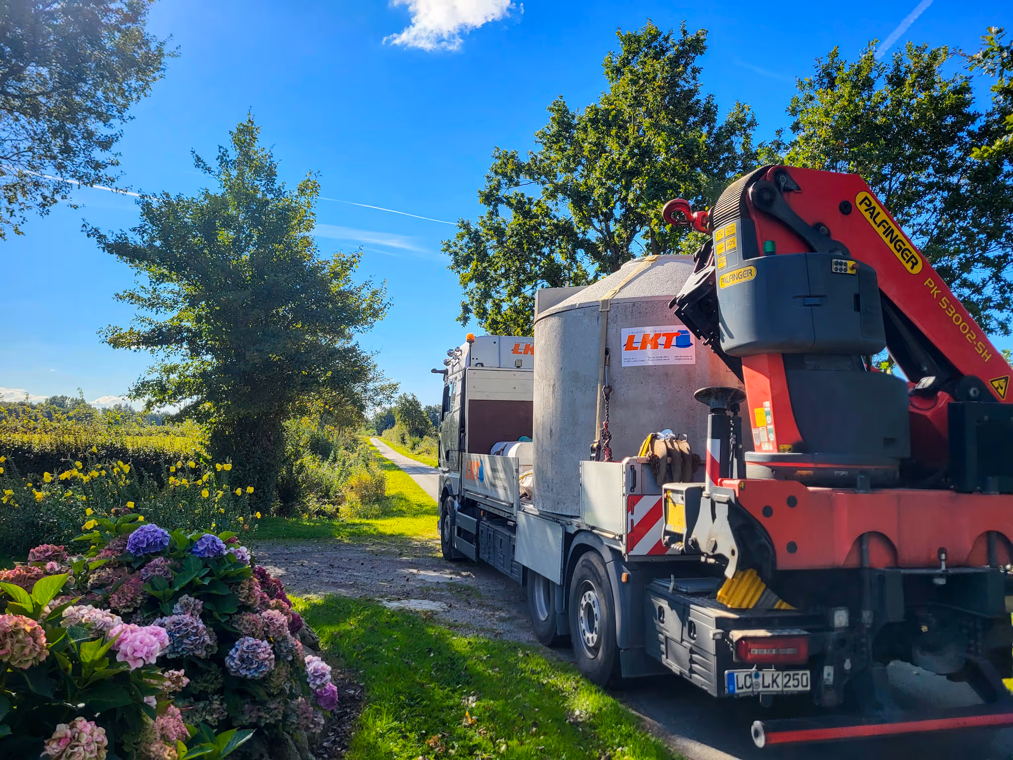 LKW mit Ladekran liefert Betonbehälter für eine Kleinkläranlage an